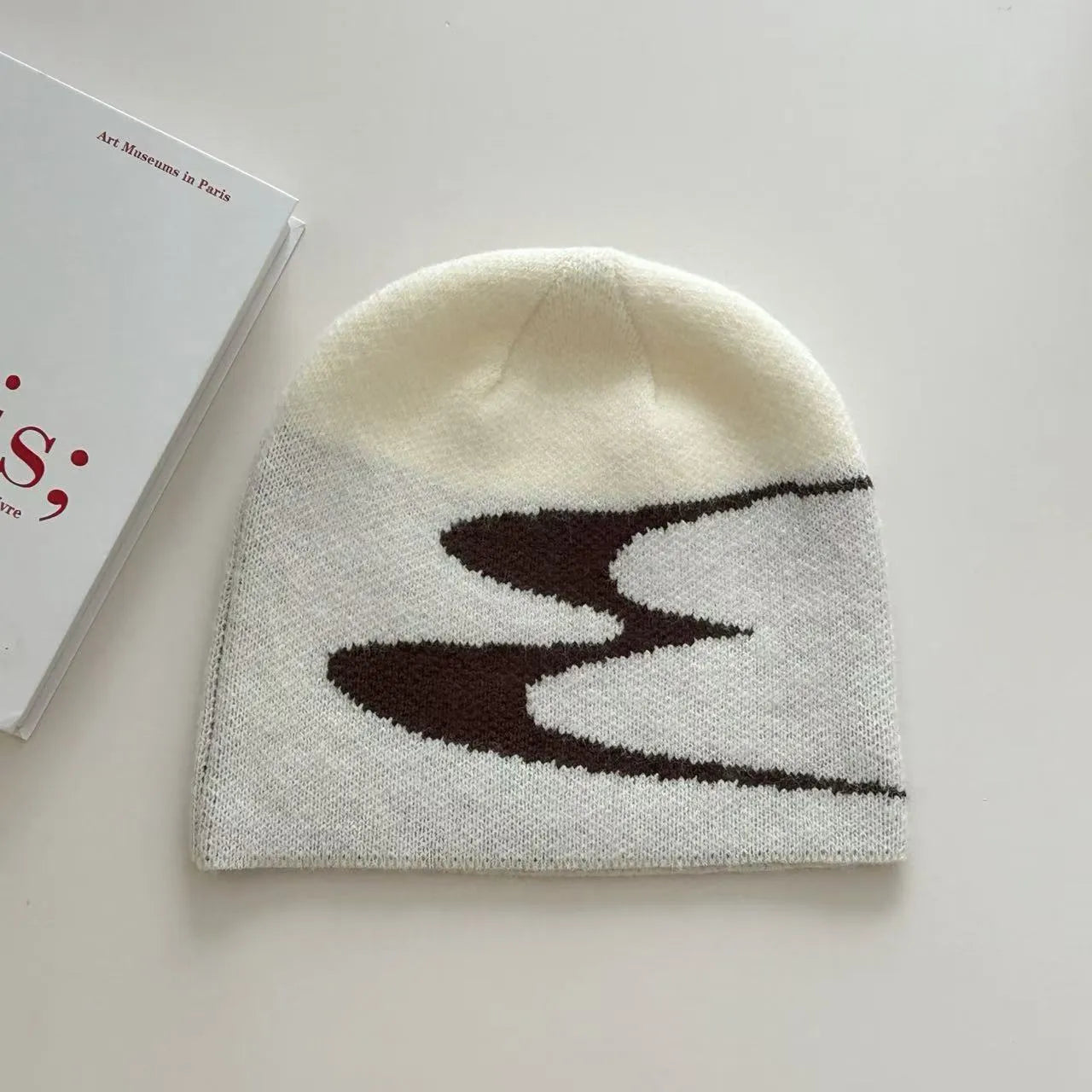 Unisex acrylic knitted beanie hat in black, shown flat.