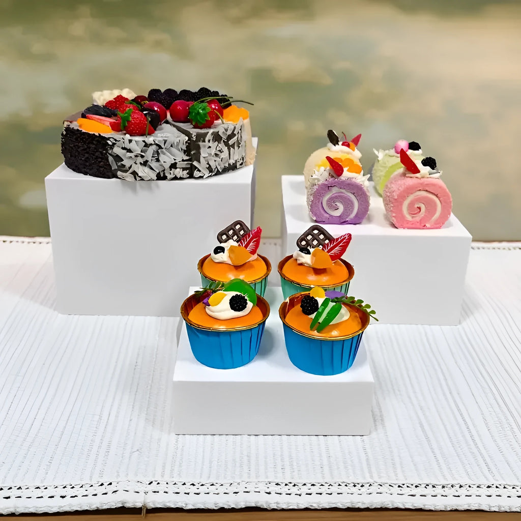 Set of six white plastic cube dessert display stands arranged on a table.