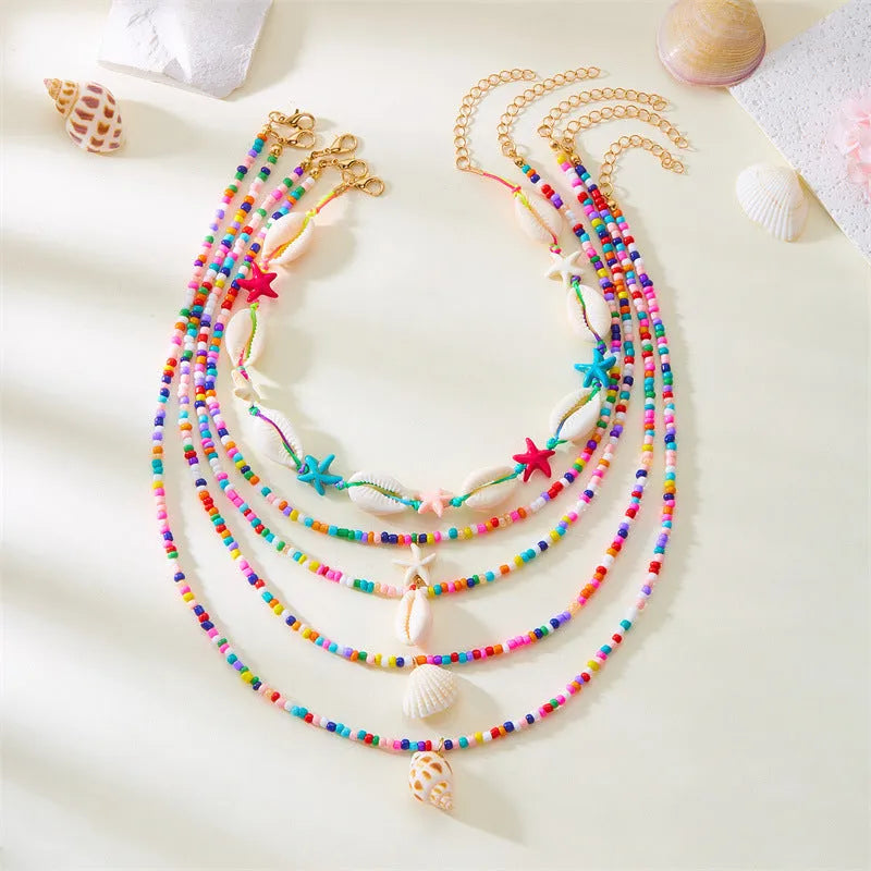 Blue and coloured women's summer necklace set with starfish, shell, and conch bead pendants on beaded chains