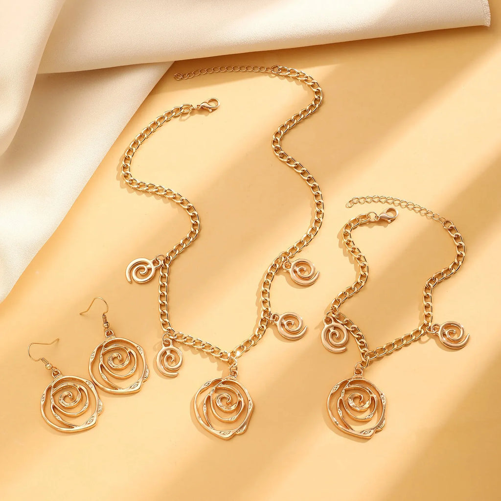 Gold spiral donut necklace, bracelet, and earrings set for women on a grey background.