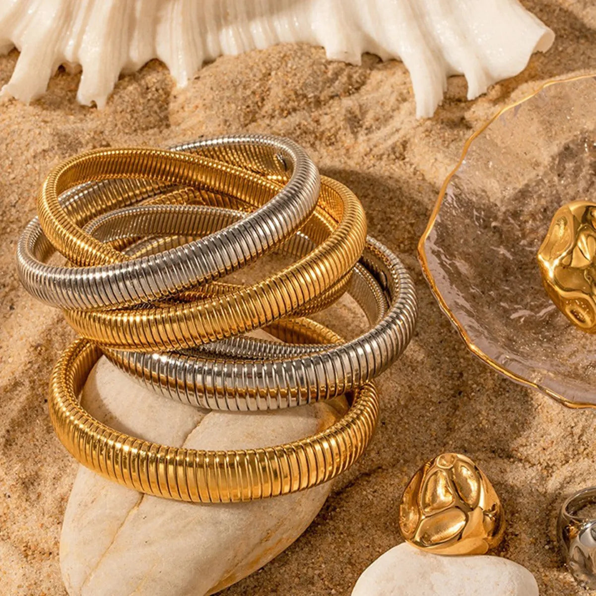 Gold titanium steel bracelet with wide vertical stripe ring pattern and elastic band on a wrist.