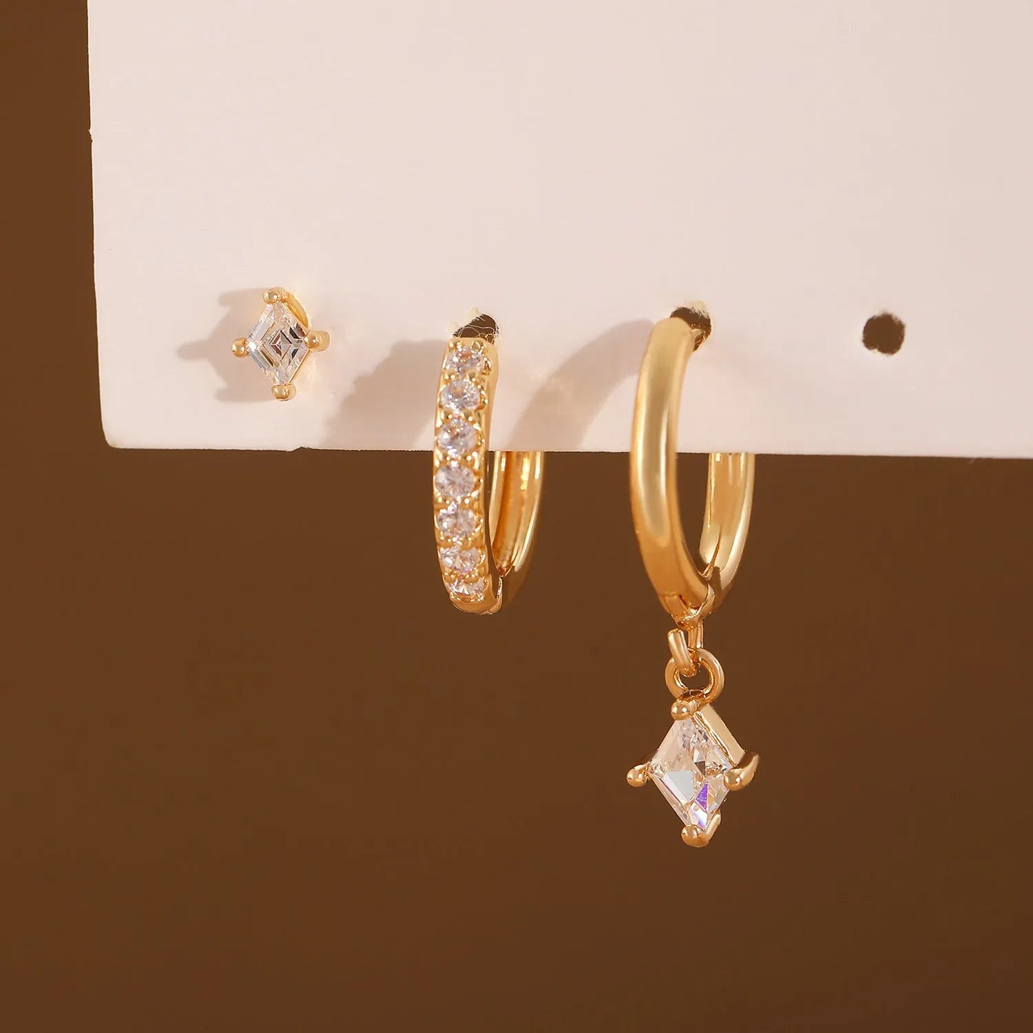 Gold and white geometric earring set with zircon stones showing three earring types: dangling, stud, and clasp.
