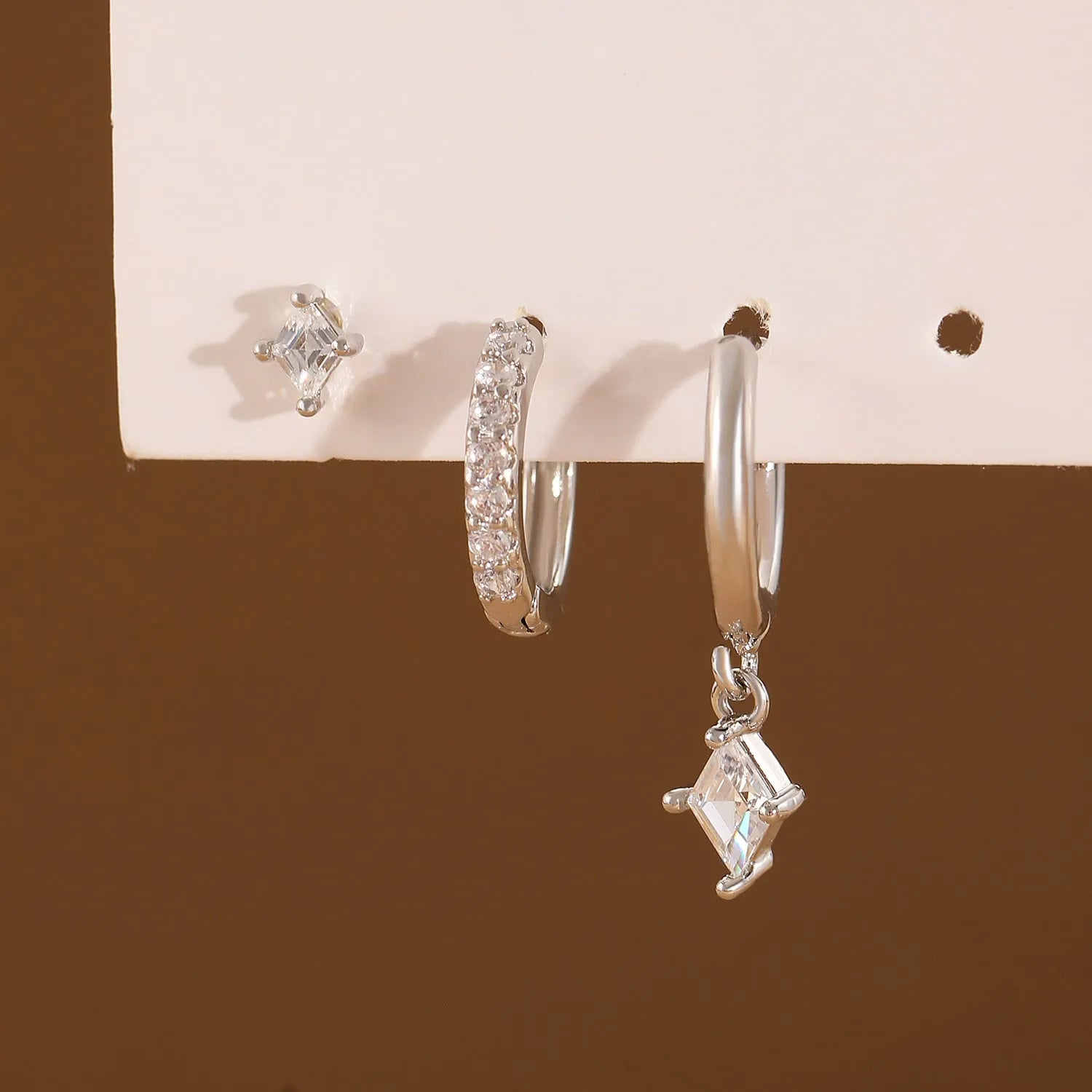 Gold and white geometric earring set with zircon stones showing three earring types: dangling, stud, and clasp.