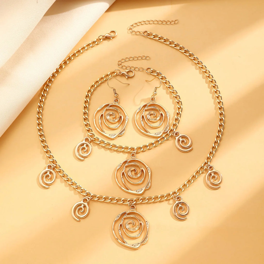 Gold spiral donut necklace, bracelet, and earrings set for women on a grey background.