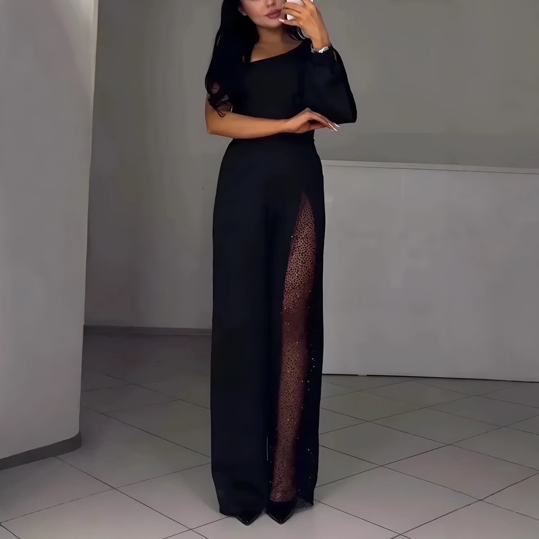 Black women's jumpsuit with oblique shoulder design and high slit on the leg.