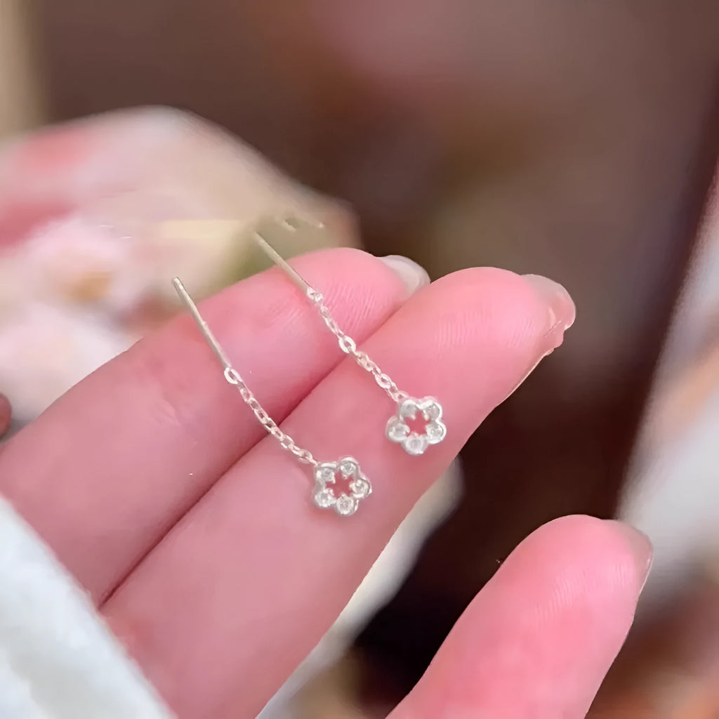 Silver-coloured alloy hollow flower hanging earrings with petal details on a white background.
