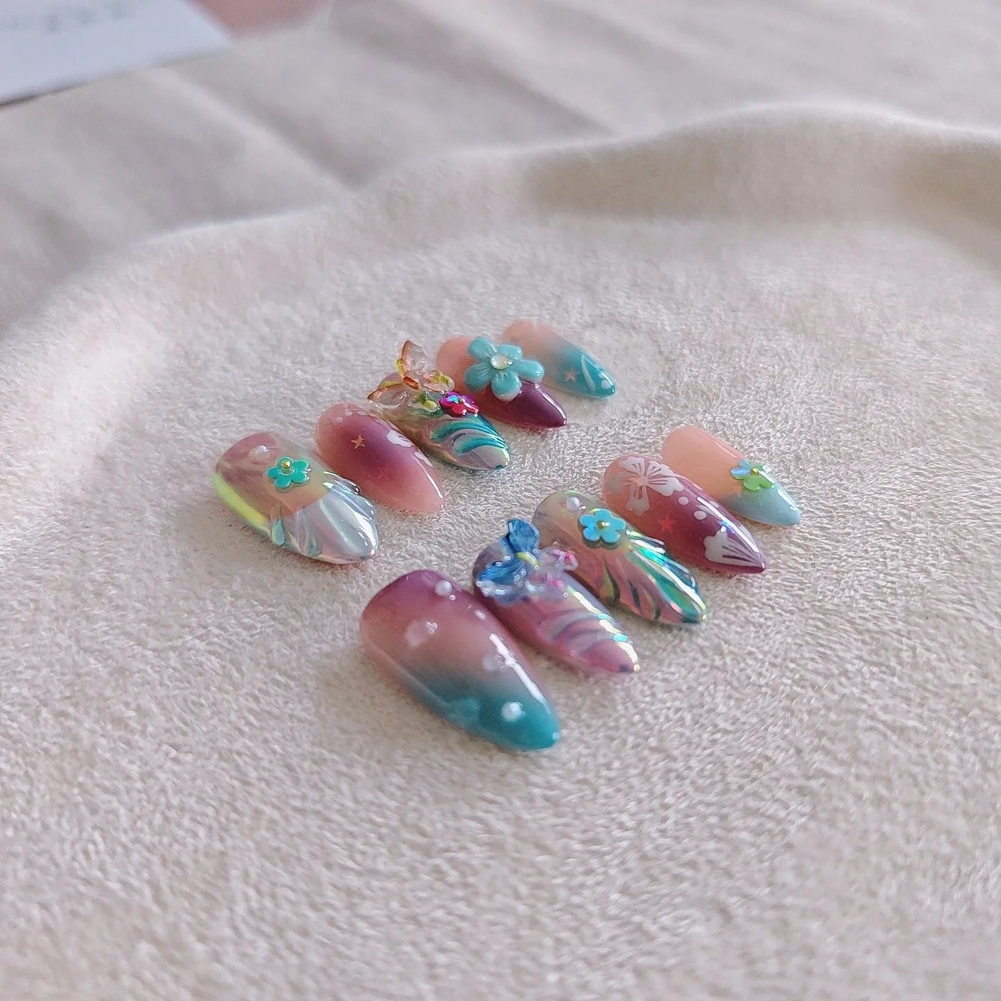 Handmade colourful false nails with embossed small flower and butterfly designs in almond shape.