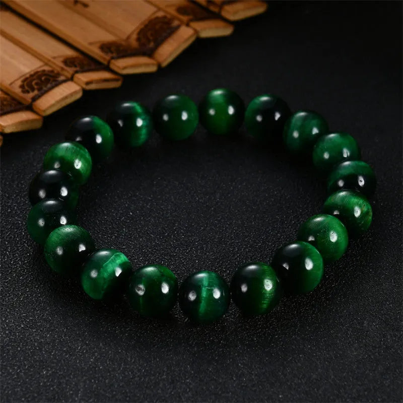 Polished green tiger eye stone beaded bracelet on a white background, showing geometric shaped beads.
