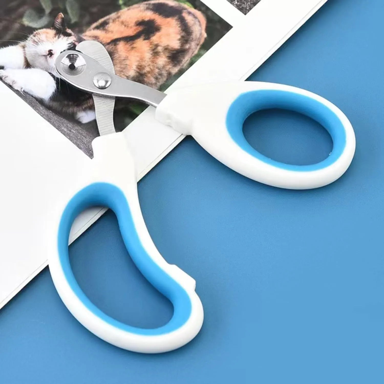 Blue cat nail clippers with circular hole and cushioned handle on a plain background