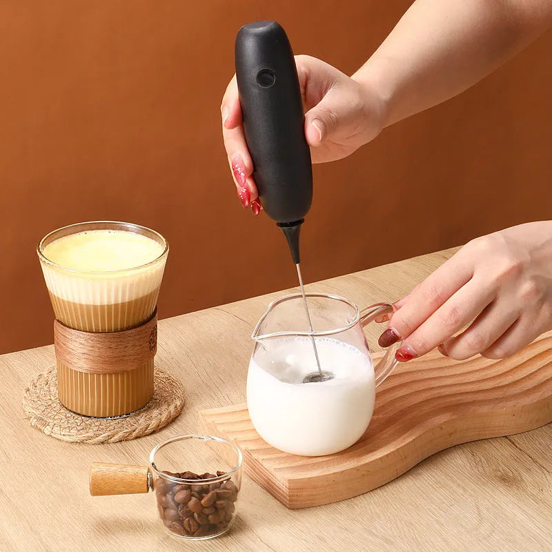 Black and white handheld electric milk frother with whisk attachment for coffee and beverage preparation