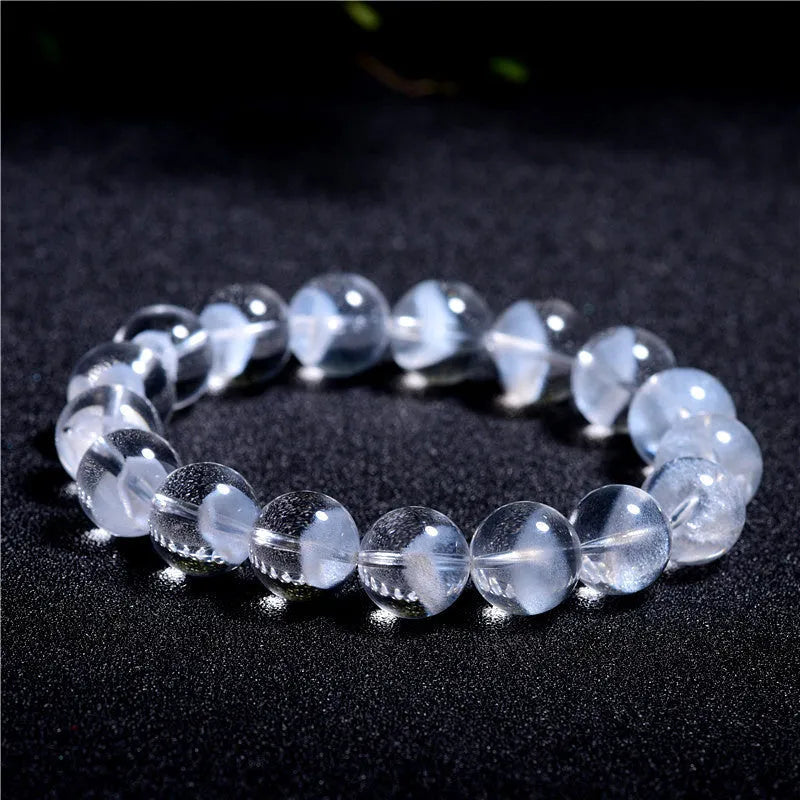 Women's white crystal pyramid bead bracelet with a Ruyi charm on a wrist.