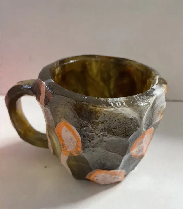 Purple and blue resin coffee mug with crystal texture and handle on wooden table