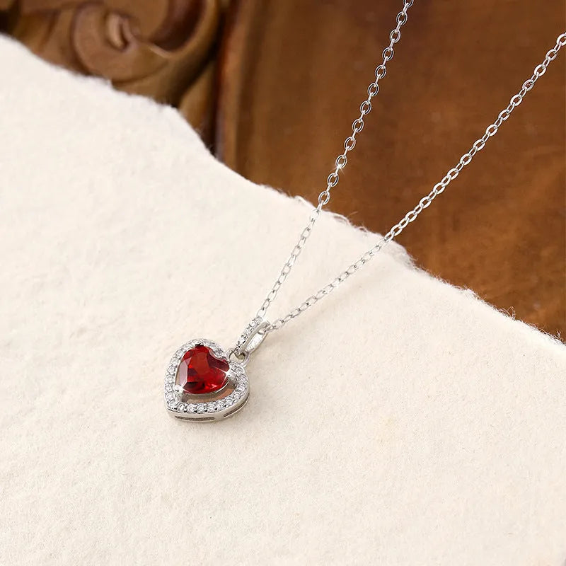 Women's sterling silver heart necklace with a round amethyst gemstone pendant on a cross chain.