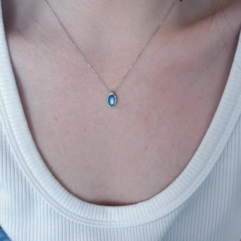 Navy blue water drop geometric pendant necklace with cross chain design on white background