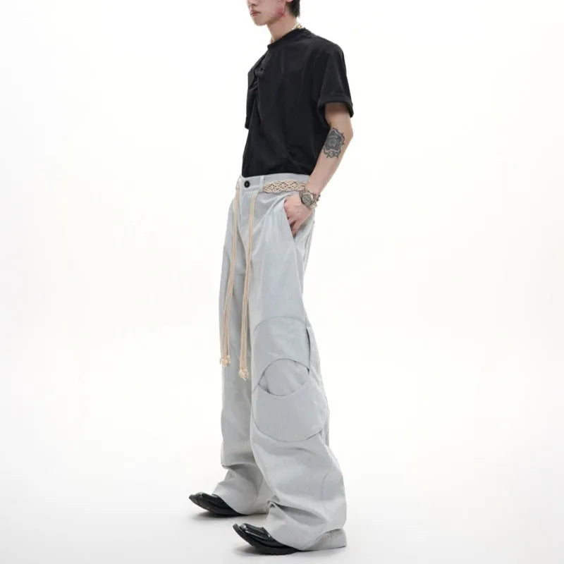 Men's dark blue straight-leg jeans showing heavy belt stitching, 3D cutting, zipper decoration, and a loose fit.