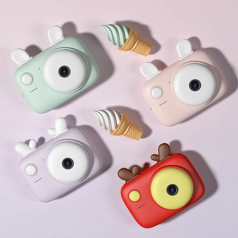 Macaron Mini SLR kids camera in green, pink, purple, or red, showing dual lenses and a 2.4-inch screen.