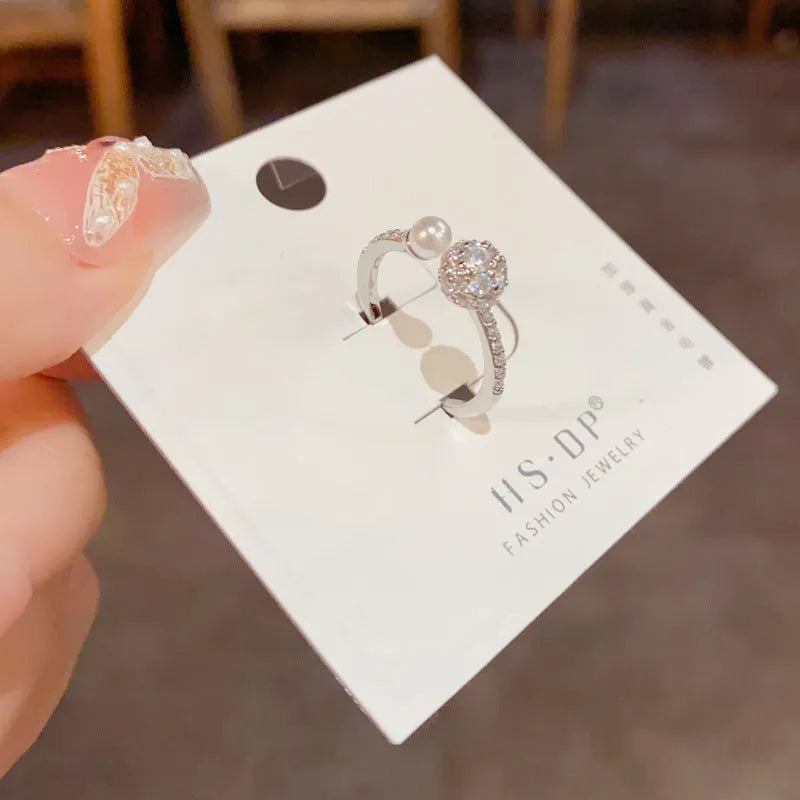 Golden round zircon open-end pearl ring with geometric shape on female hand