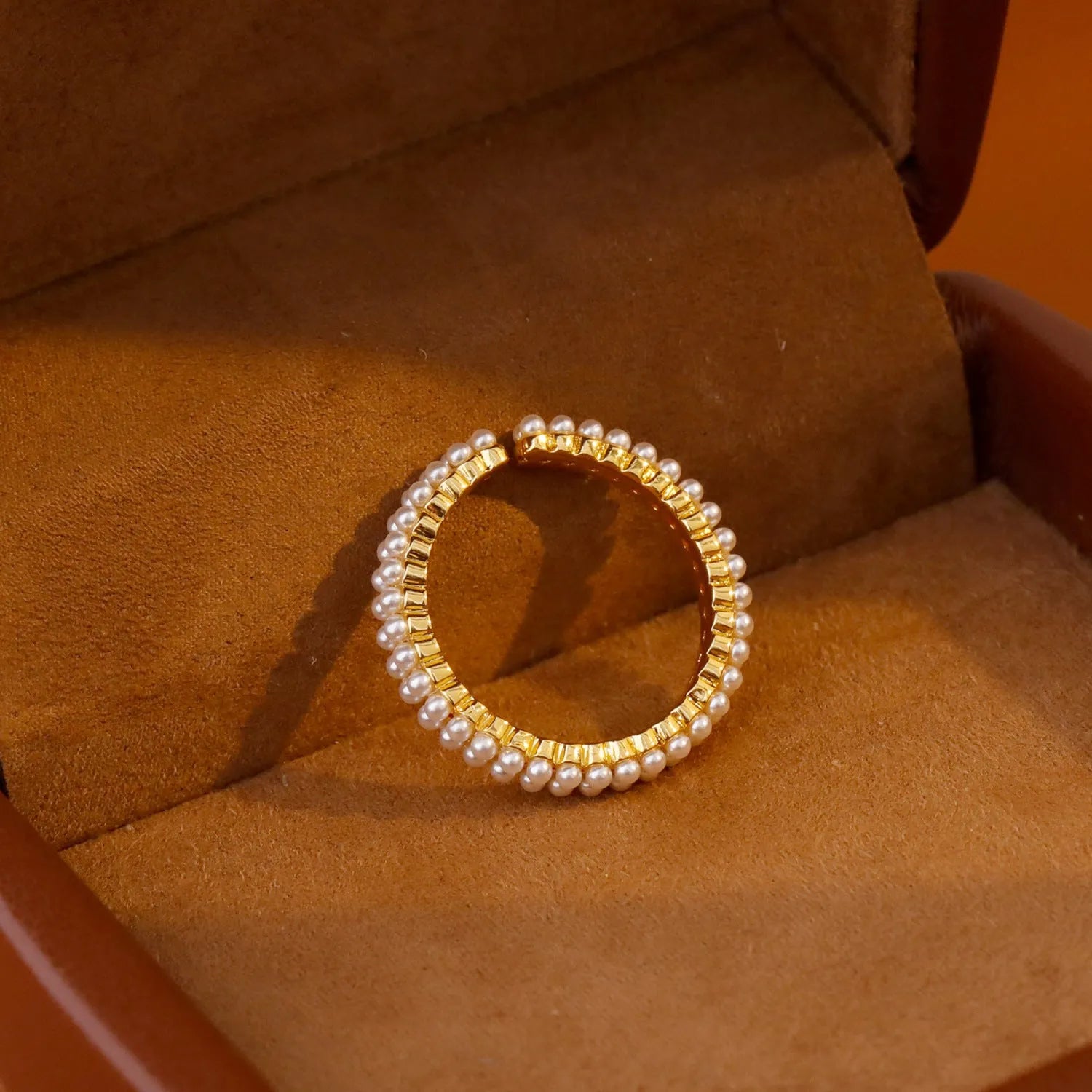 Gold geometric open ring for women with round pearls on a white background.