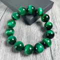 Polished green tiger eye stone beaded bracelet on a white background, showing geometric shaped beads.
