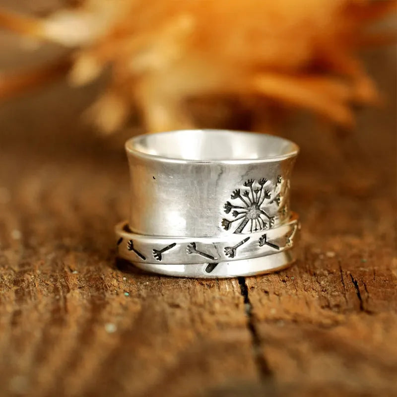 Silver coloured rotatable floral fashion ring on a hand, showing the spinning flower design.