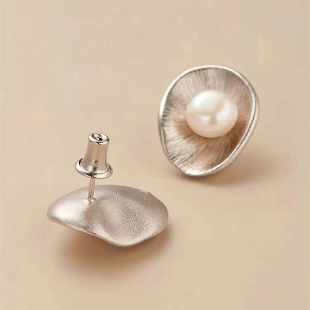 A pair of silver geometric pearl ear studs with gold electroplated finish on needle posts.