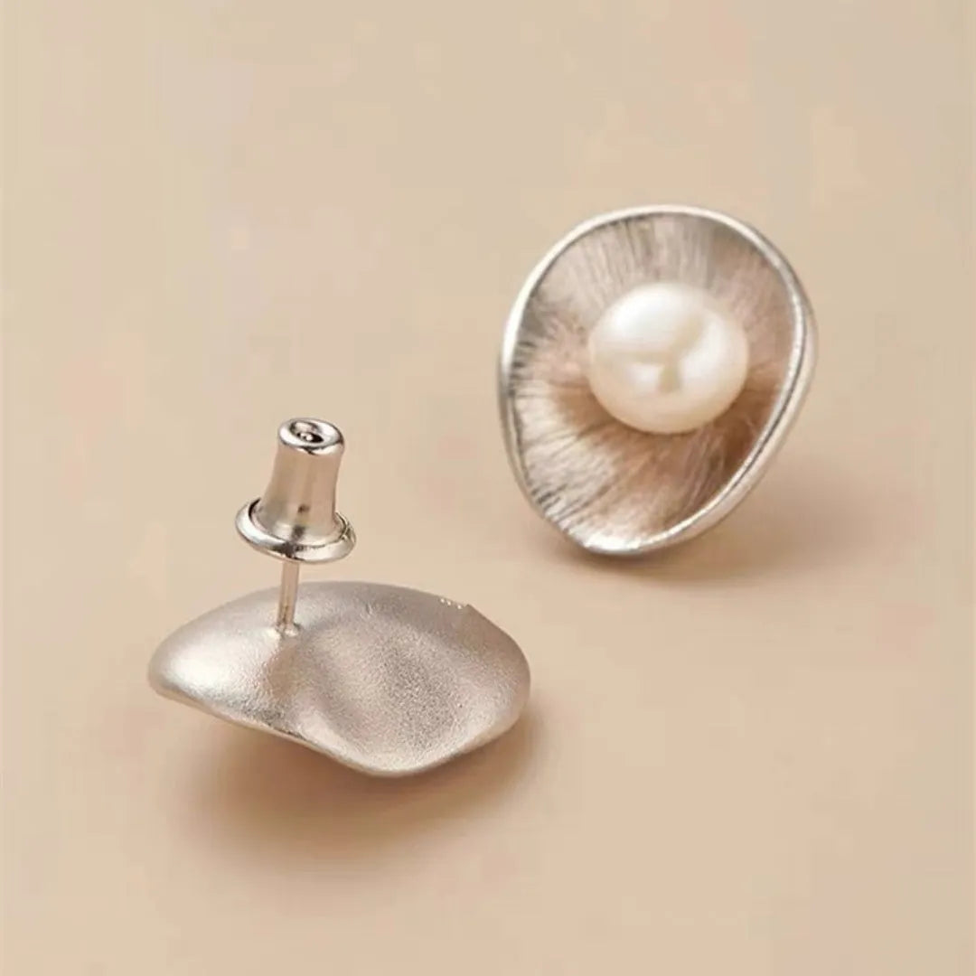 A pair of silver geometric pearl ear studs with gold electroplated finish on needle posts.