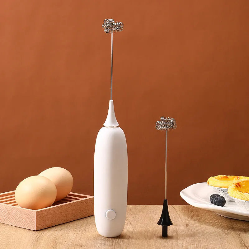 Black and white handheld electric milk frother with whisk attachment for coffee and beverage preparation