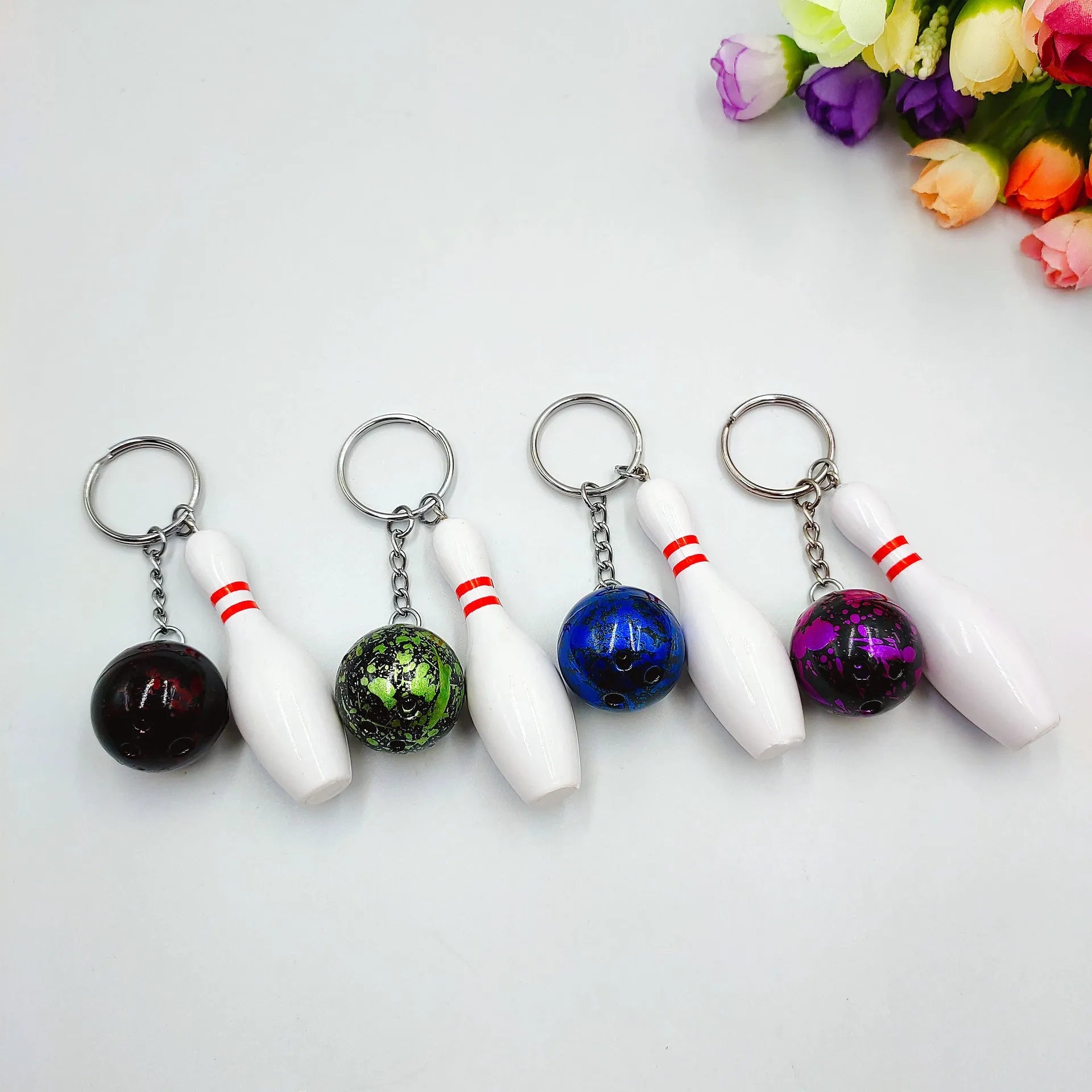 Mini bowling ball simulation keychain in blue, red, purple, and green colours.