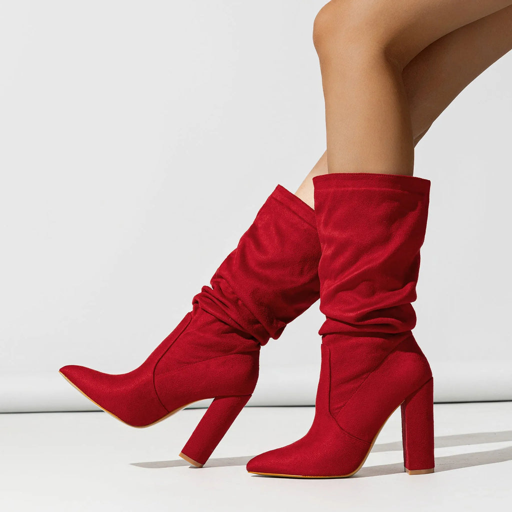 Women's black suede pointed-toe boots with a chunky high heel on a neutral background.