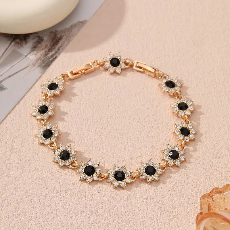 Electroplated zinc alloy bracelet with flower-shaped coloured gems in gold or silver tone.