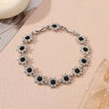 Electroplated zinc alloy bracelet with flower-shaped coloured gems in gold or silver tone.