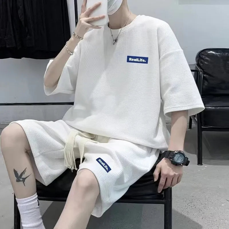 Man wearing a grey waffle-textured cotton blend short sleeve top and matching shorts leisure set.