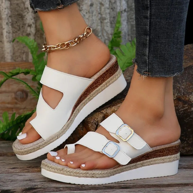 White patent leather women's wedge sandals with a woven design and peep toe on a rubber sole.