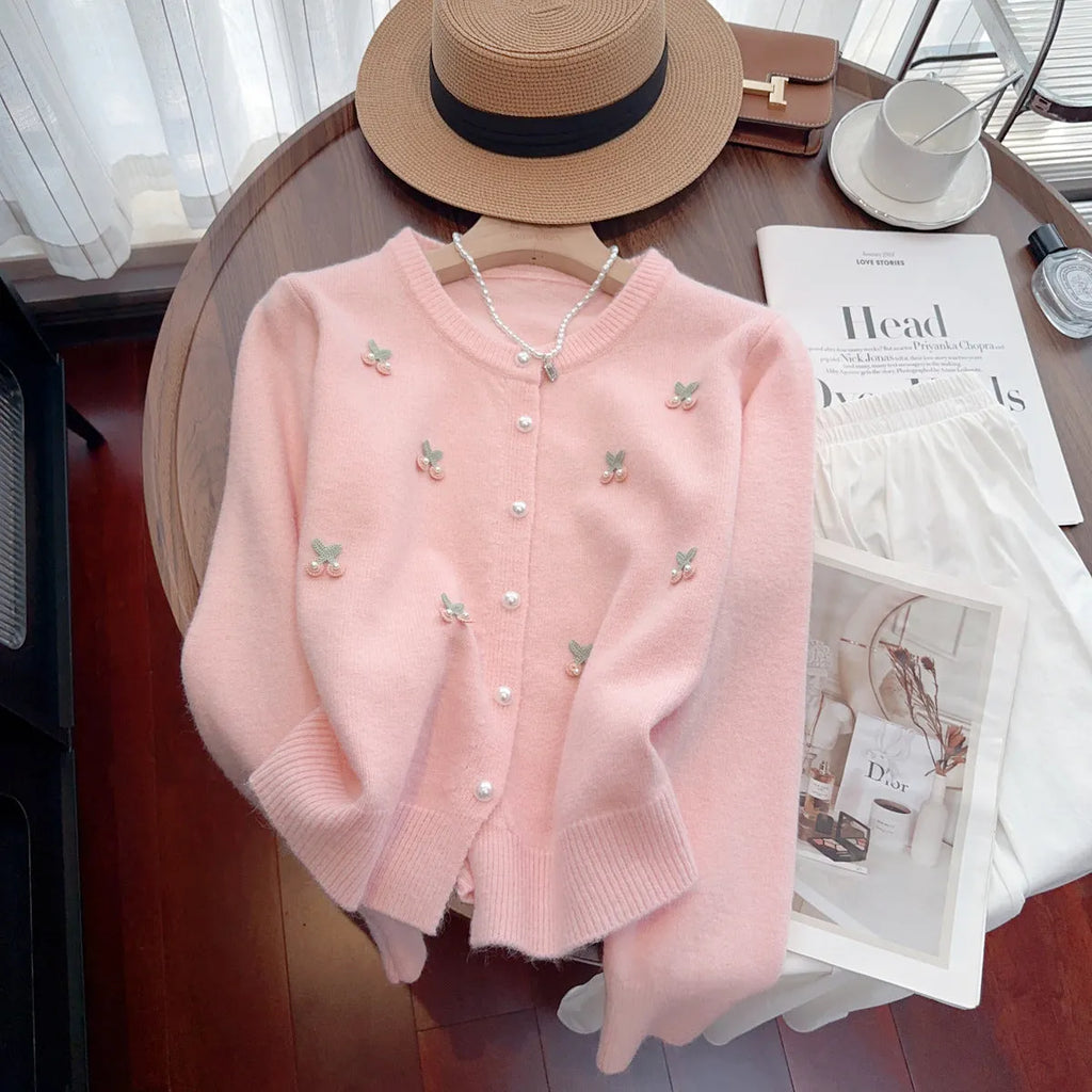 A pink cashmere blend women's cardigan sweater coat with beaded detailing and a round neck, shown open.