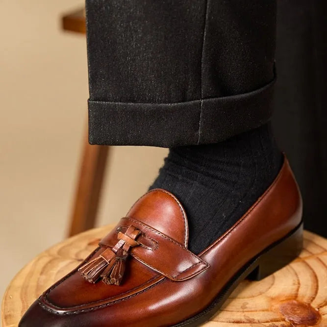 Men's black leather tassel loafers with polished finish and rubber soles for business casual wear
