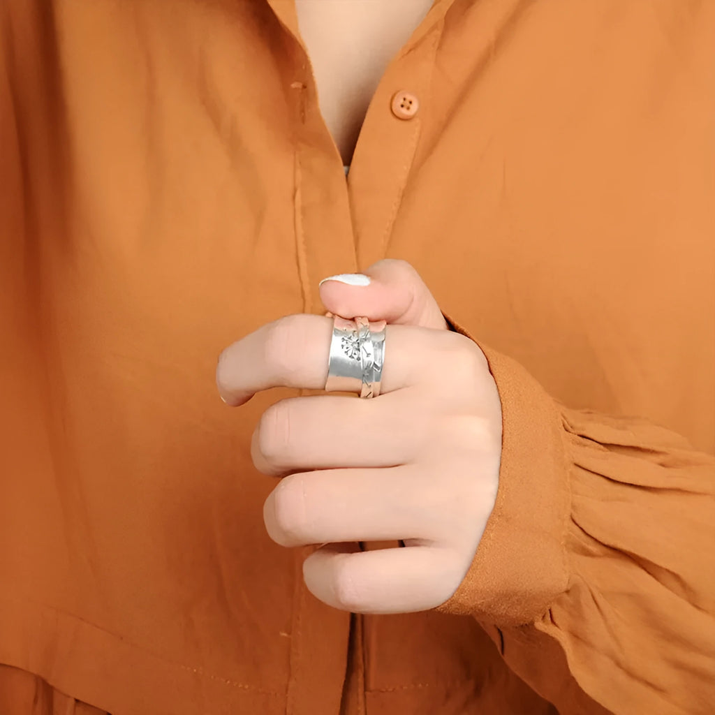 Silver coloured rotatable floral fashion ring on a hand, showing the spinning flower design.