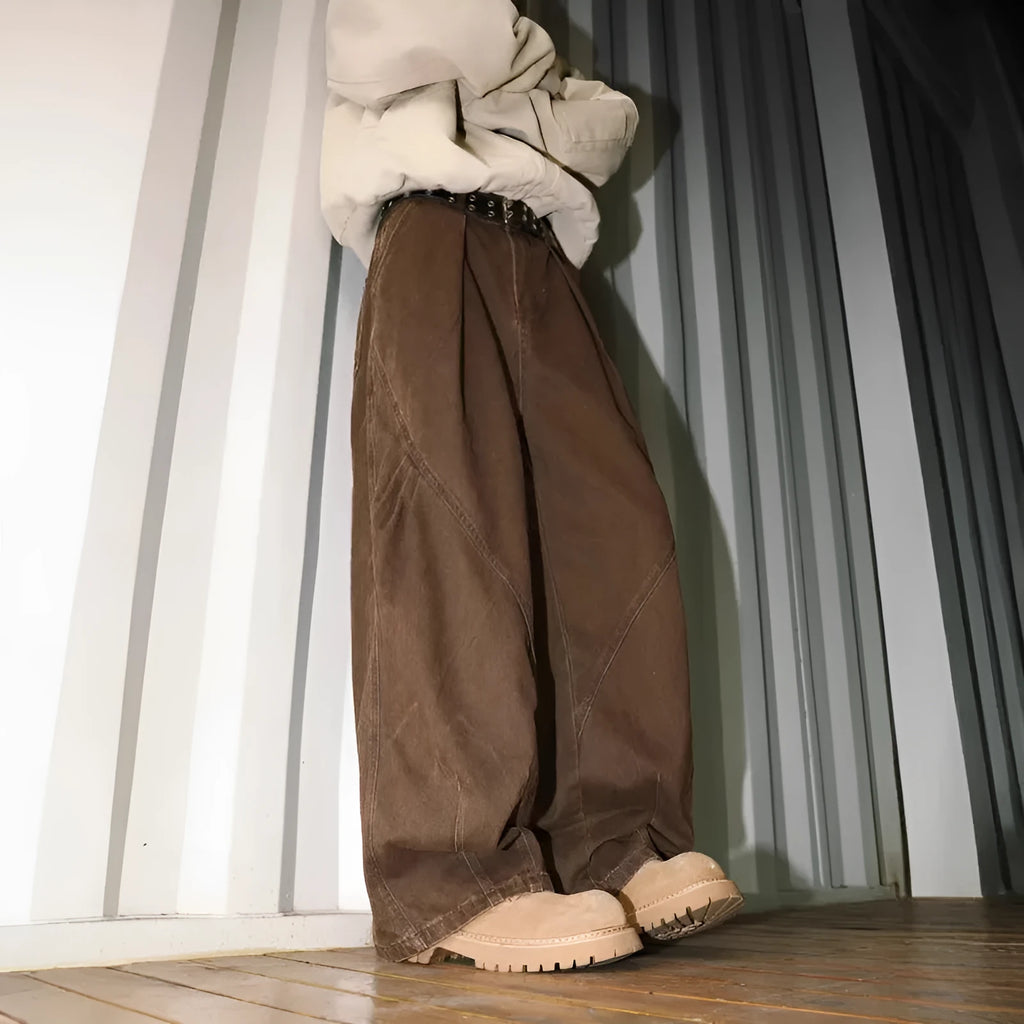 Man wearing straight-leg pleated trousers in a cotton-polyester blend, available in black, brown, and apricot.