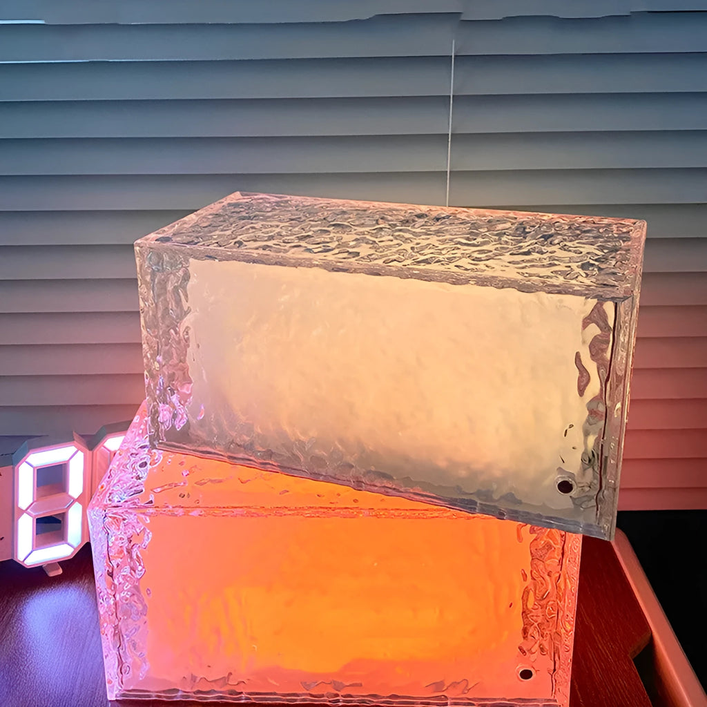 Geometric ice cube shaped clear acrylic LED night light on a table.