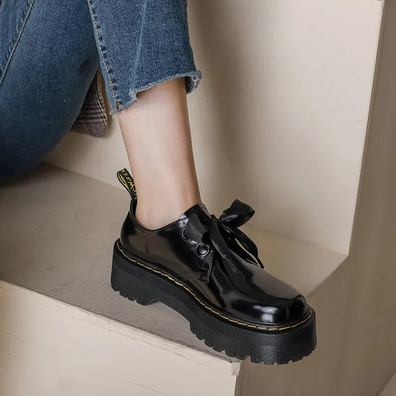 Women's black leather lace-up shoes with thick soles and cross-strap ribbons on the upper.