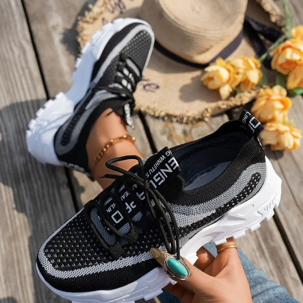 Women's Flyknit mesh lace-up sneakers in a grey colourway showing round toe and low profile.