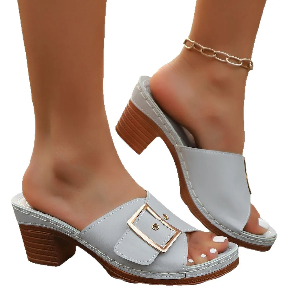 Women's black chunky heel slippers with a silver metal buckle and rubber sole on a light background.