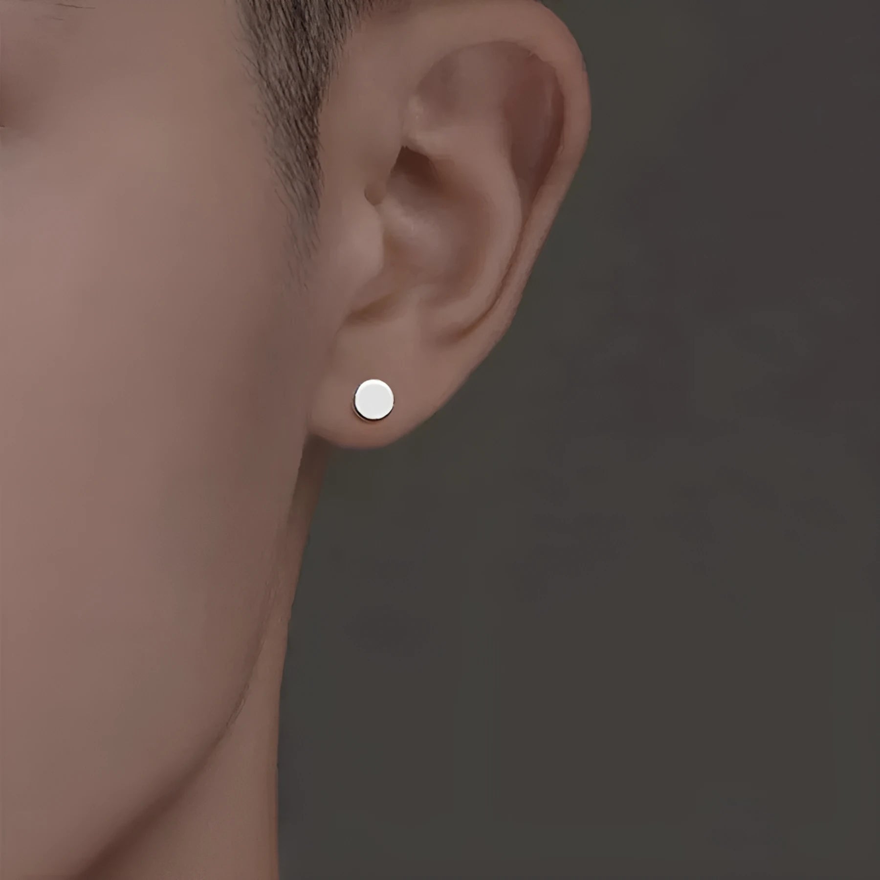 A pair of small, round, flat sterling silver stud earrings for cartilage piercing on a plain background.