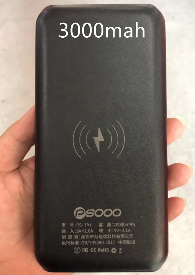Black portable solar power bank with wireless charging pad and three USB ports on a wooden surface.