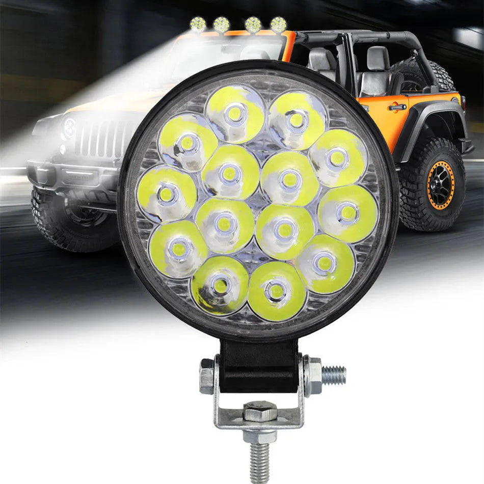 White mini round LED work light with aluminium housing, mounted as an auxiliary car or truck light.