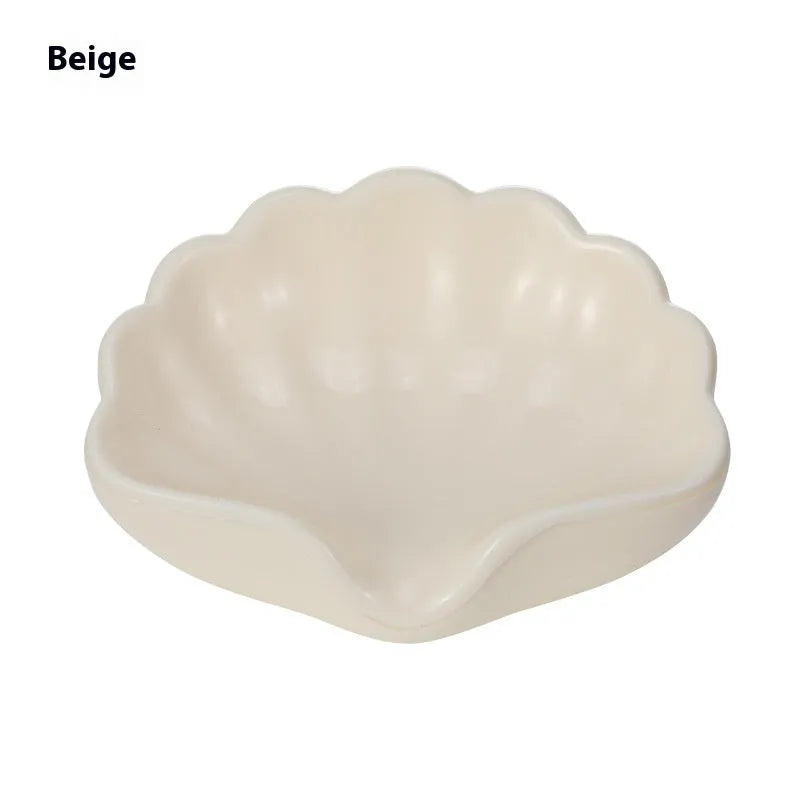 White shell-shaped plastic soap dish with drainage holes on a bathroom counter.