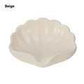 White shell-shaped plastic soap dish with drainage holes on a bathroom counter.