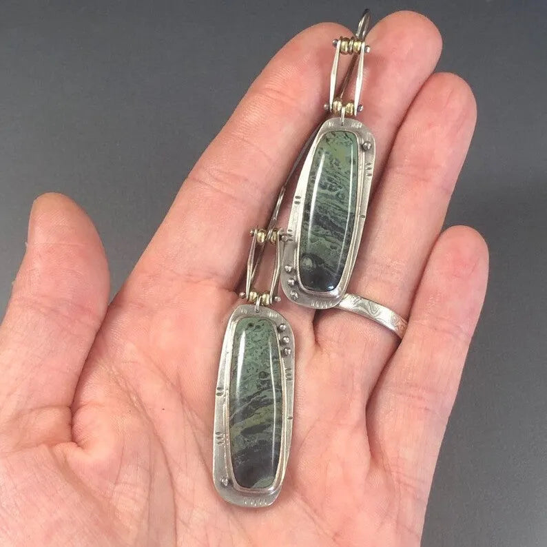 Geometric alloy earrings with a white and grey marble pattern on a simple background.