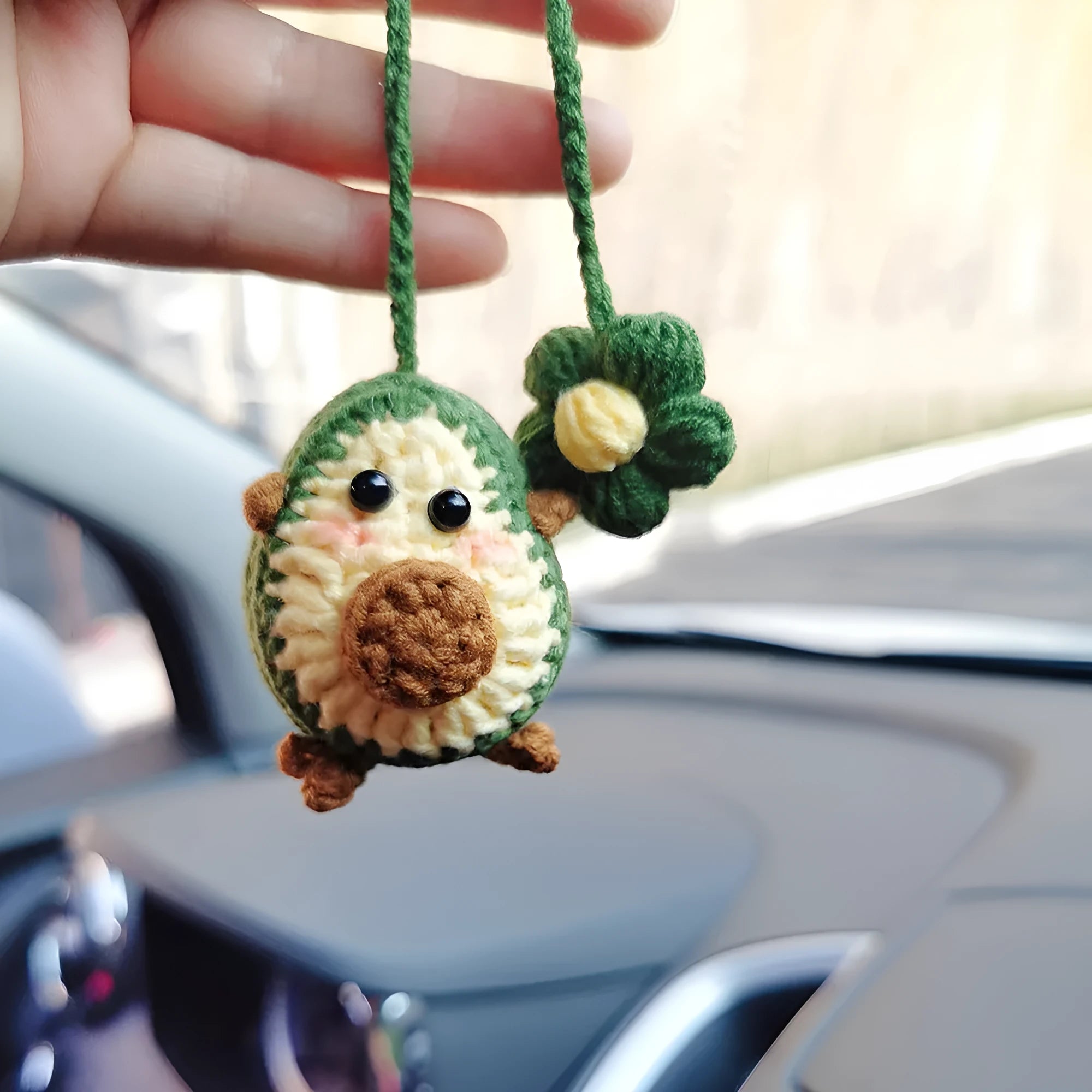 Handmade crocheted wool car pendant with a cartoon flower in avocado, pink rainbow, or red rainbow colours.