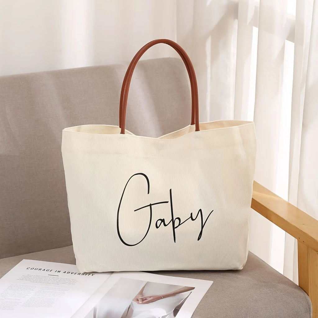 Beige white canvas tote bag with cotton handles, showing interior patch pocket and exterior zipper pocket.