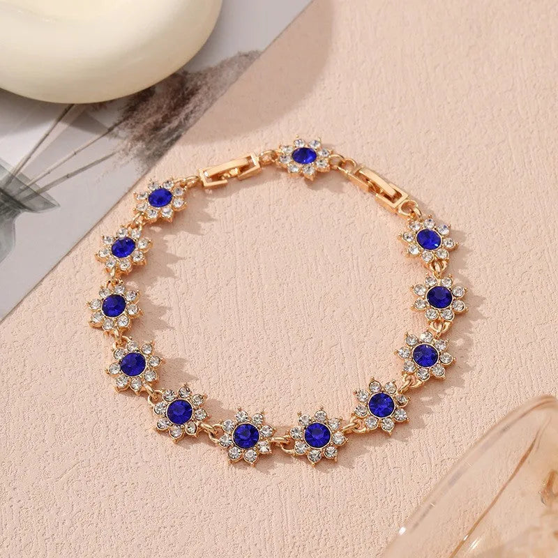 Electroplated zinc alloy bracelet with flower-shaped coloured gems in gold or silver tone.
